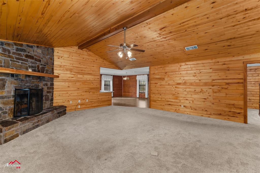 6951 Mira Myrtis Road Ida, LA 71044 - Photo 16 of 32 Unfurnished living room featuring lofted ceiling with beams, a ceiling fan, carpet, and a fireplace