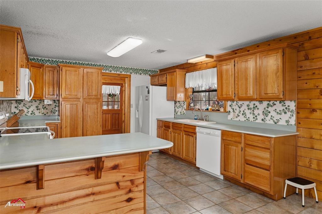 6951 Mira Myrtis Road Ida, LA 71044 - Photo 18 of 32 Kitchen featuring light countertops, visible vents, a peninsula, white appliances, and a sink