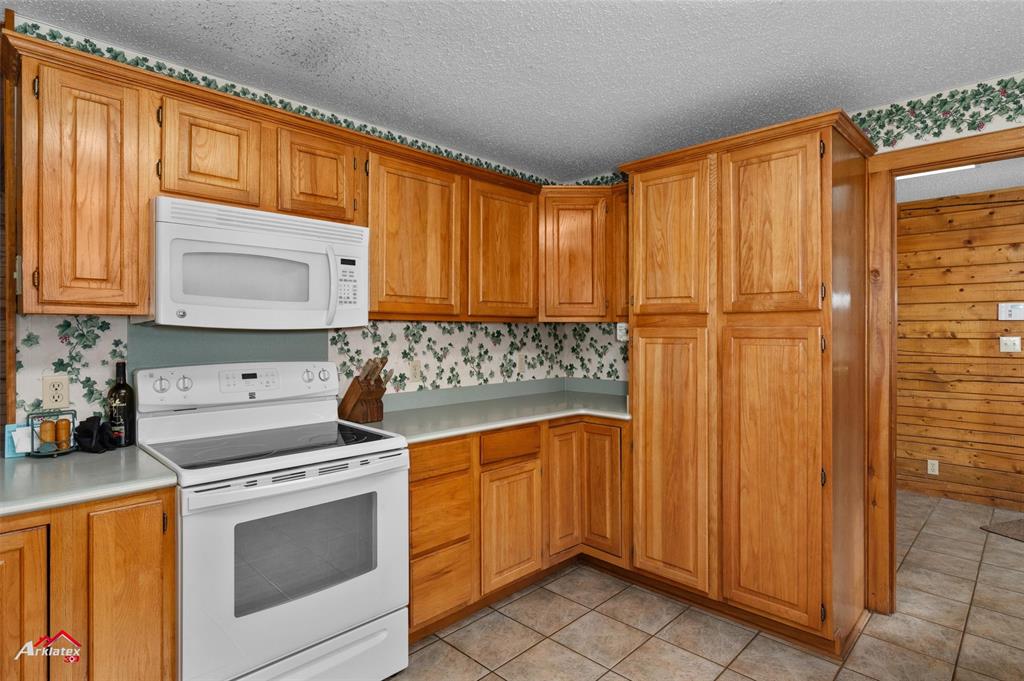 6951 Mira Myrtis Road Ida, LA 71044 - Photo 19 of 32 Kitchen featuring light countertops, light tile patterned floors, a textured ceiling, and white appliances