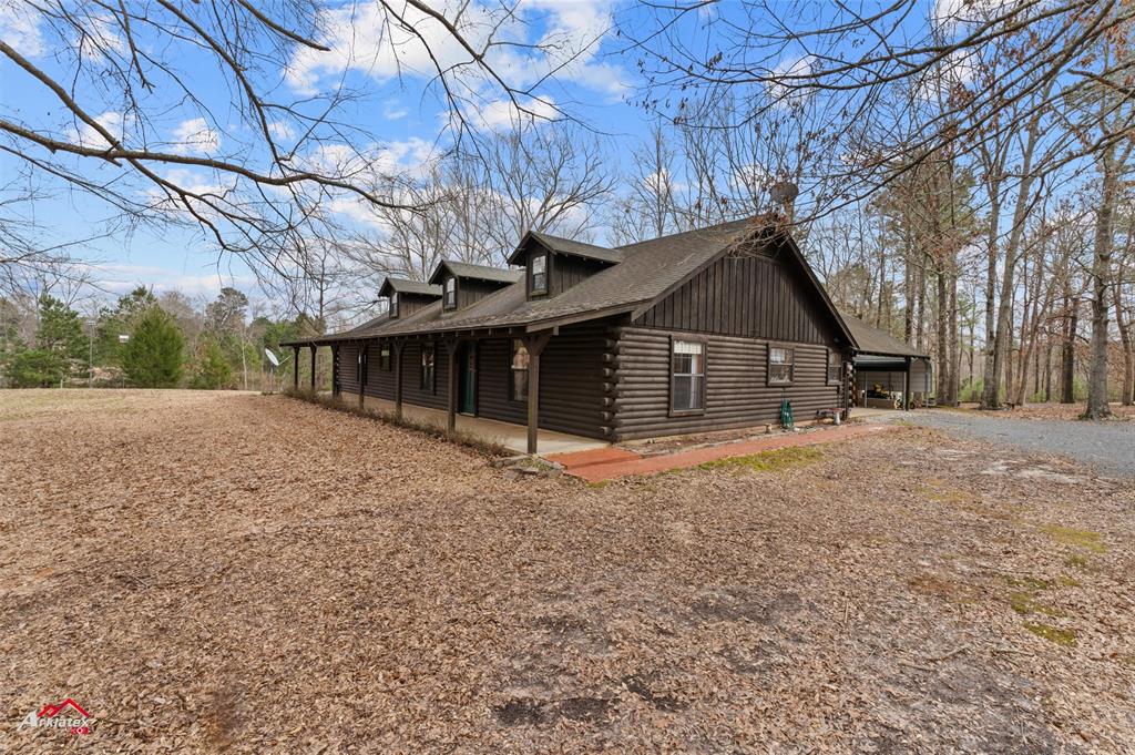 6951 Mira Myrtis Road Ida, LA 71044 - Photo 2 of 32 View of side of home with roof with shingles, gravel driveway, board and batten siding, and log exterior