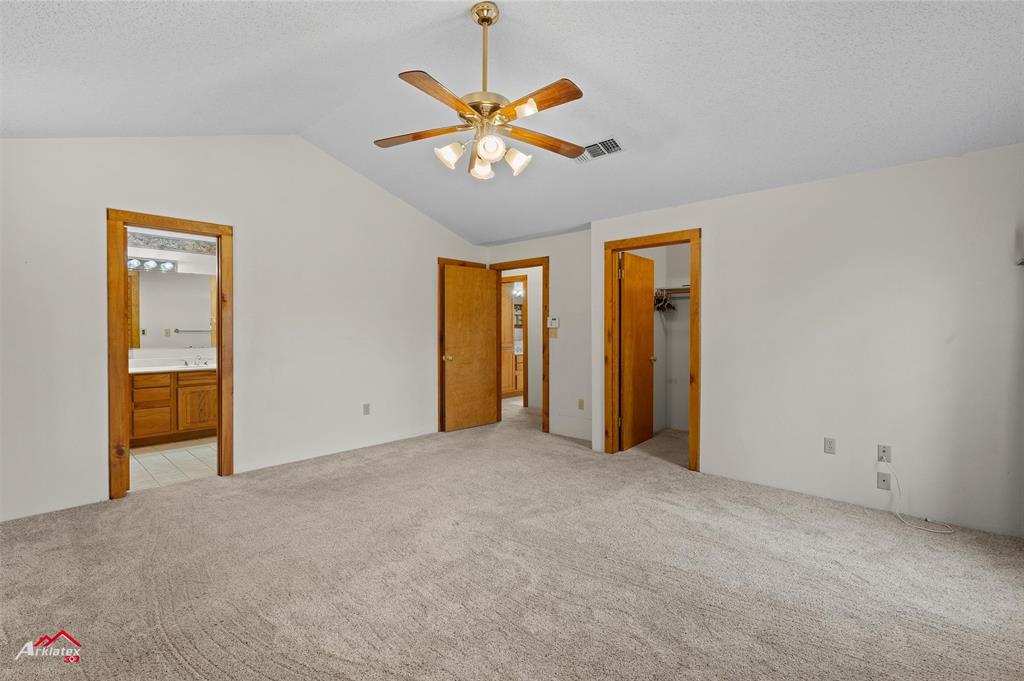 6951 Mira Myrtis Road Ida, LA 71044 - Photo 22 of 32 Unfurnished bedroom featuring connected bathroom, a spacious closet, lofted ceiling, light colored carpet, and visible vents