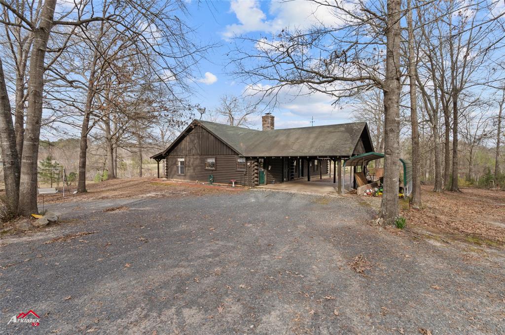 6951 Mira Myrtis Road Ida, LA 71044 - Photo 5 of 32 View of front facade with log exterior, driveway, a carport, and a chimney