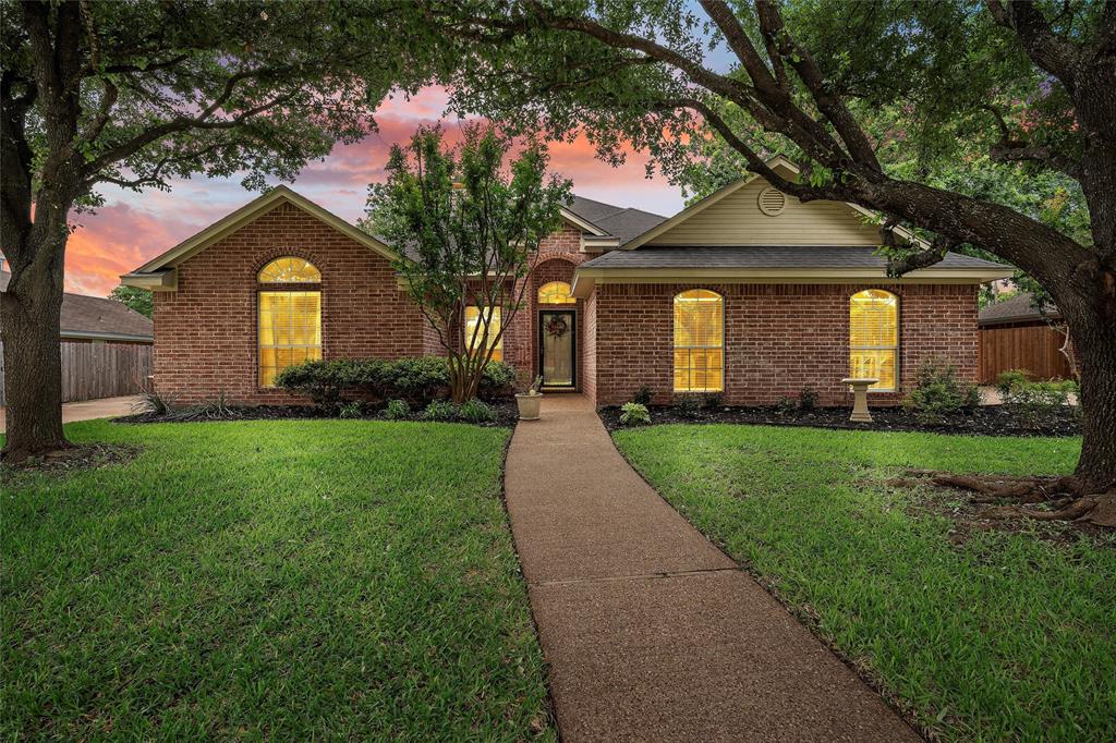 a front view of a house with a yard and large tree