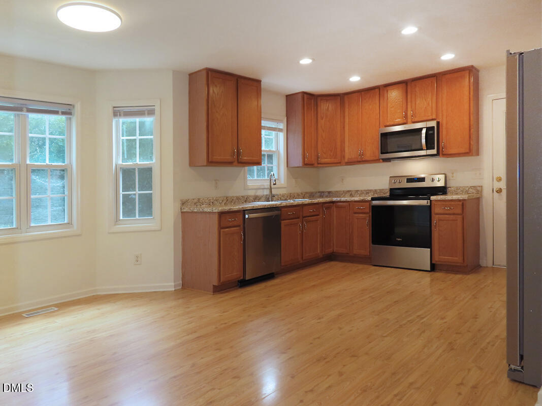 304 Davie Road Carrboro, NC 27510 - Photo 8 of 18 a kitchen with stainless steel appliances granite countertop a stove top oven a sink dishwasher a refrigerator and cabinets with wooden floor