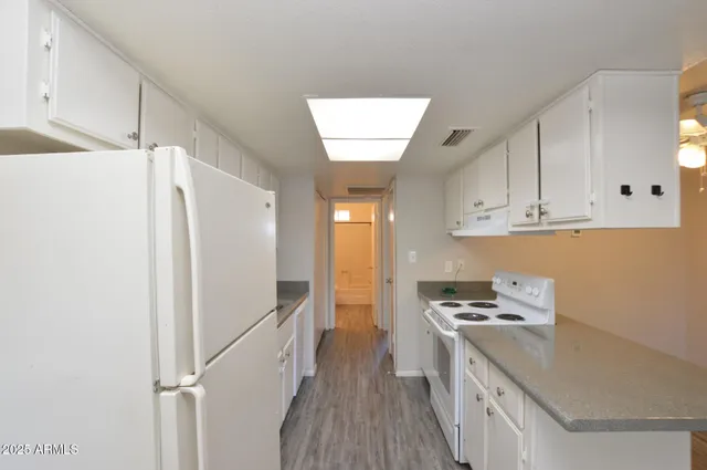 a kitchen with stainless steel appliances a refrigerator a sink a stove and white cabinets