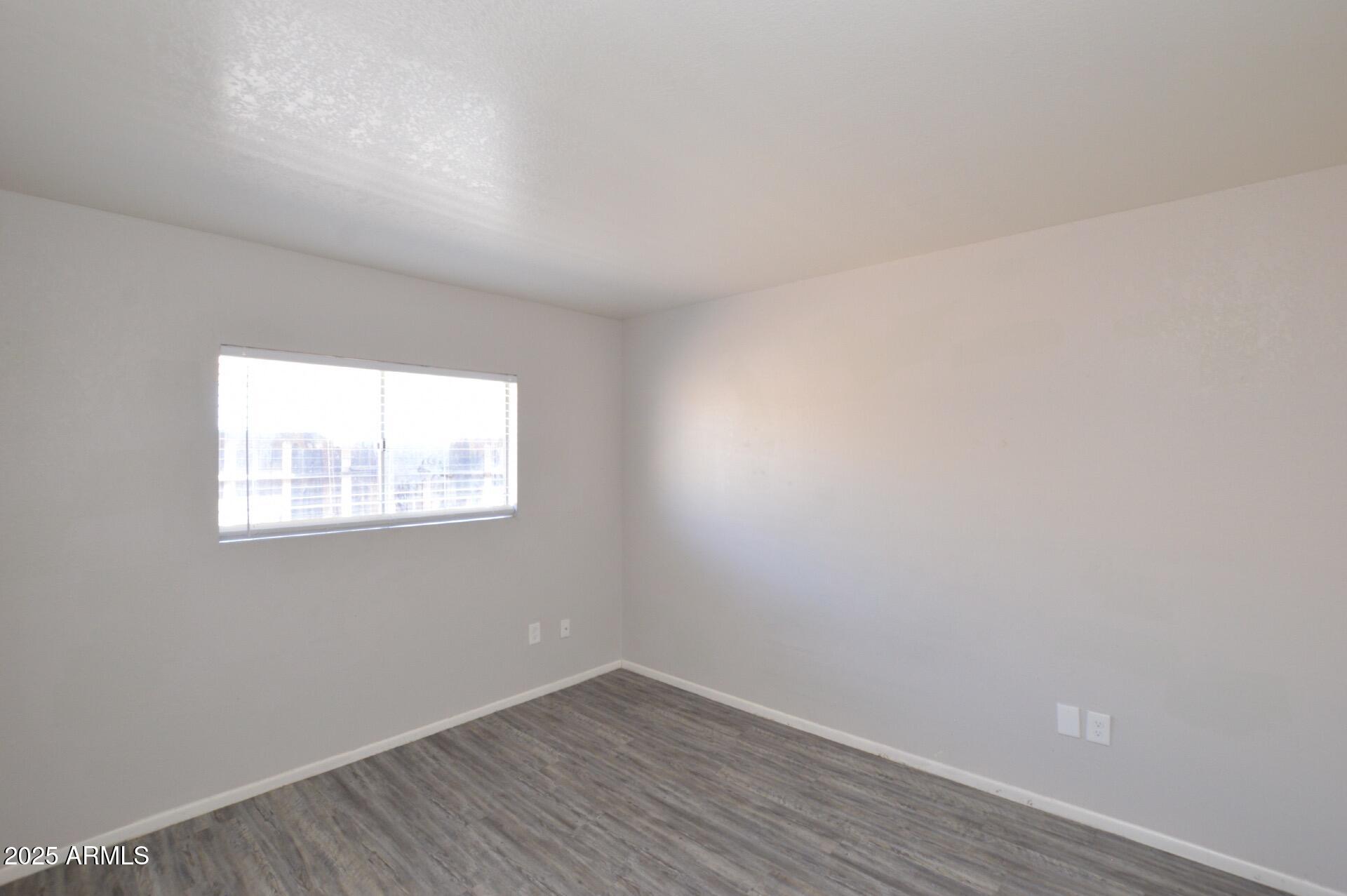 3004 East Waltann Lane, Unit 7 Phoenix, AZ 85032 - Photo 10 of 12 an empty room with wooden floor and windows