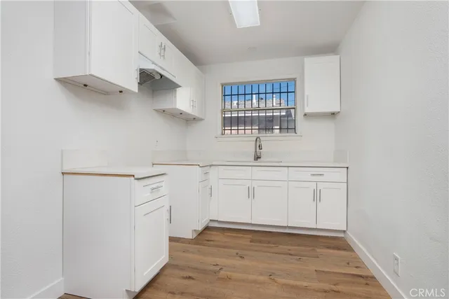 a kitchen with white cabinets and window