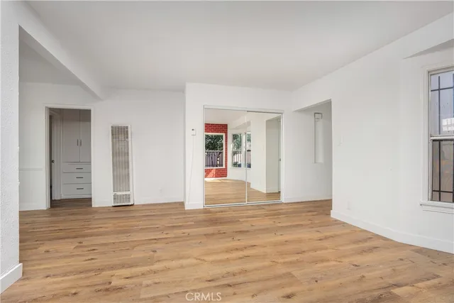 a view of an empty room with wooden floor and window