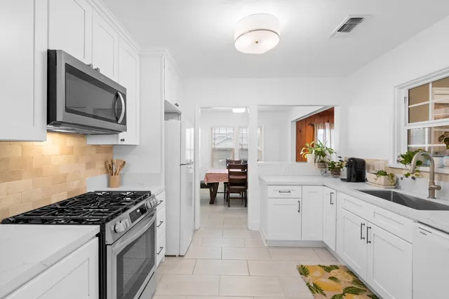 a kitchen with stainless steel appliances white cabinets and stove top oven