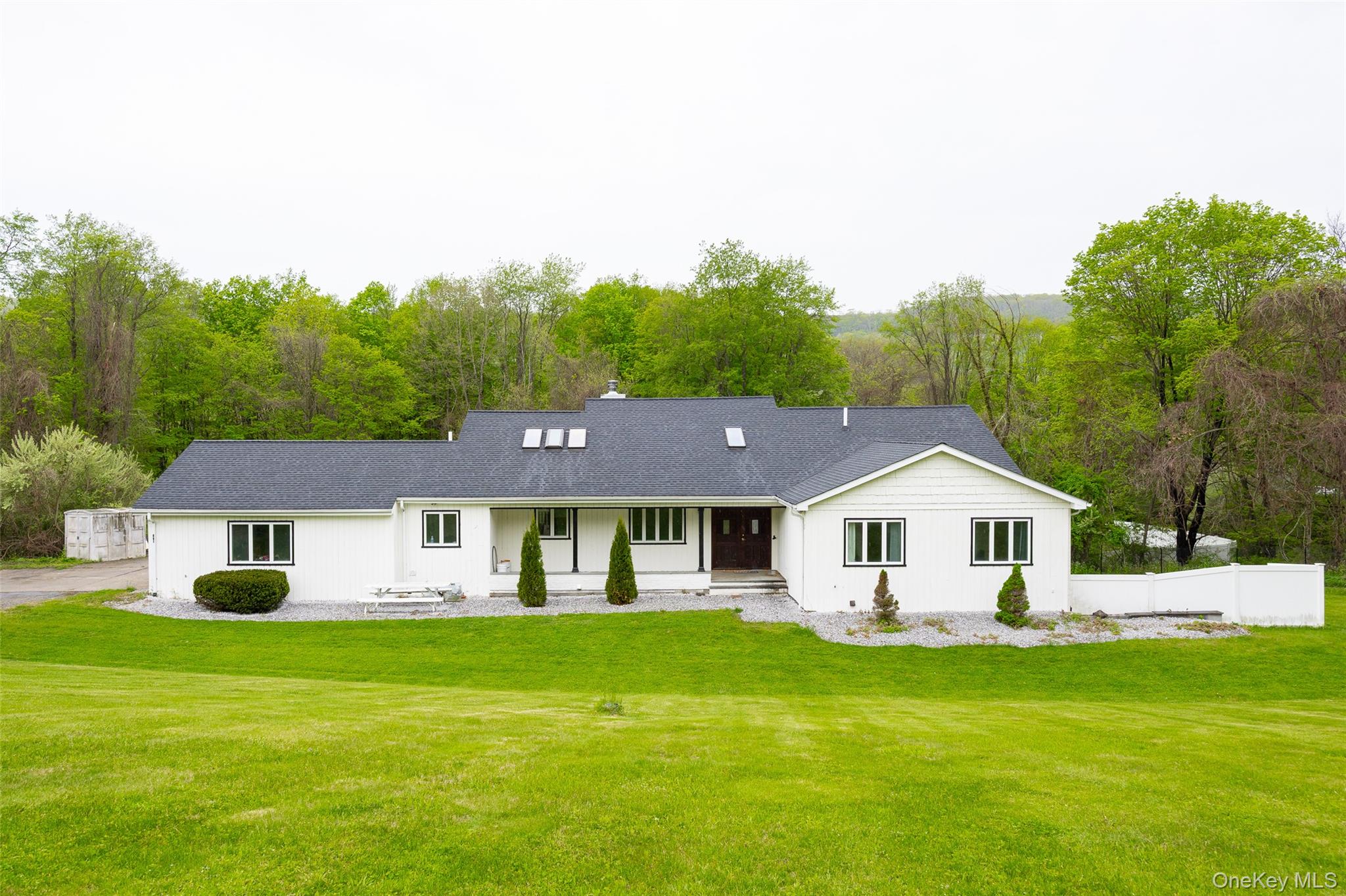 Ranch-style residence featuring white siding and a dark shingle roof