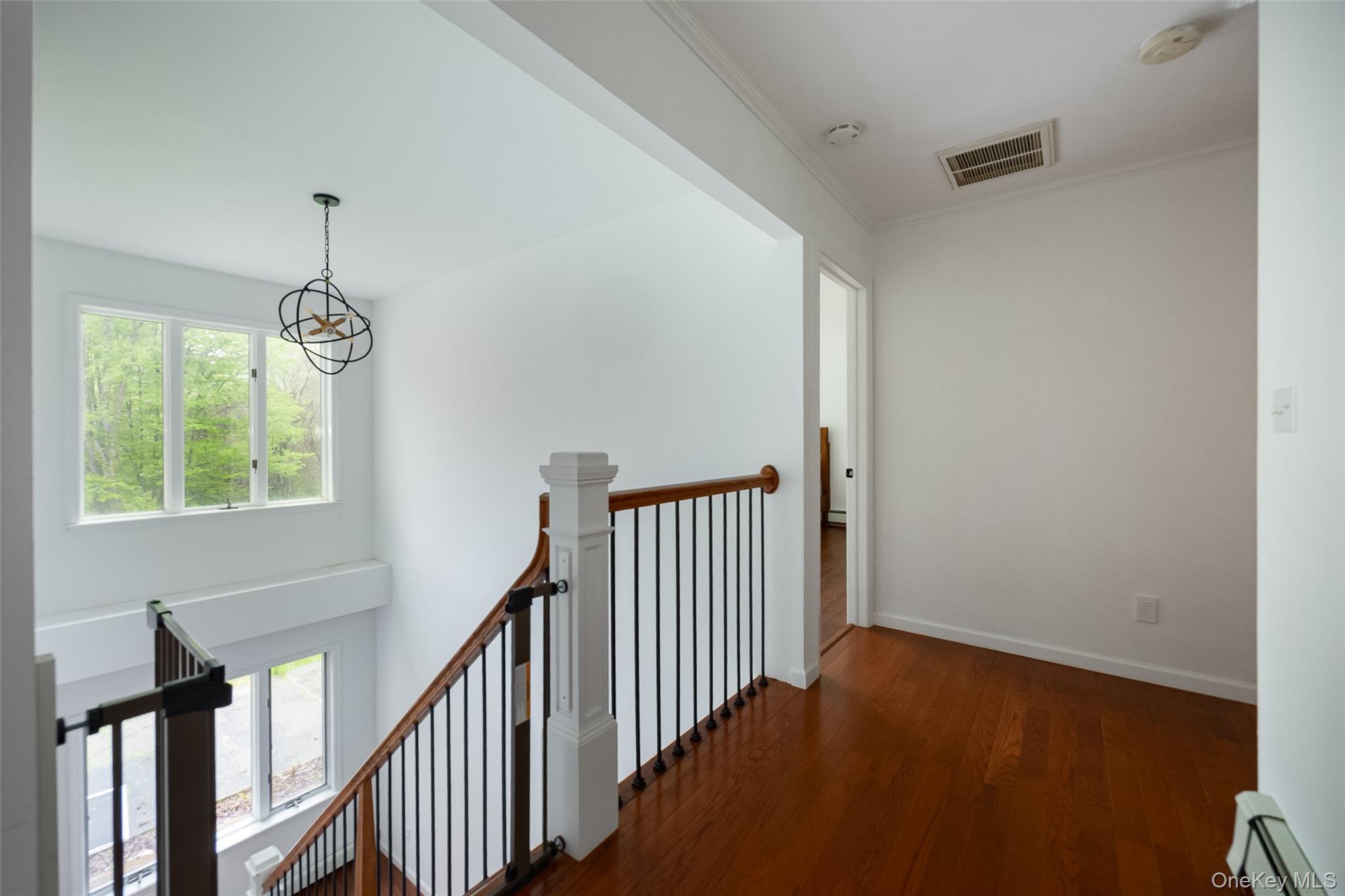 921 West Dover Road Pawling, NY 12564 - Photo 20 of 36 Upper-level landing featuring wood-finish flooring, a contemporary chandelier, a white balustrade with dark spindles, and natural light from multiple windows