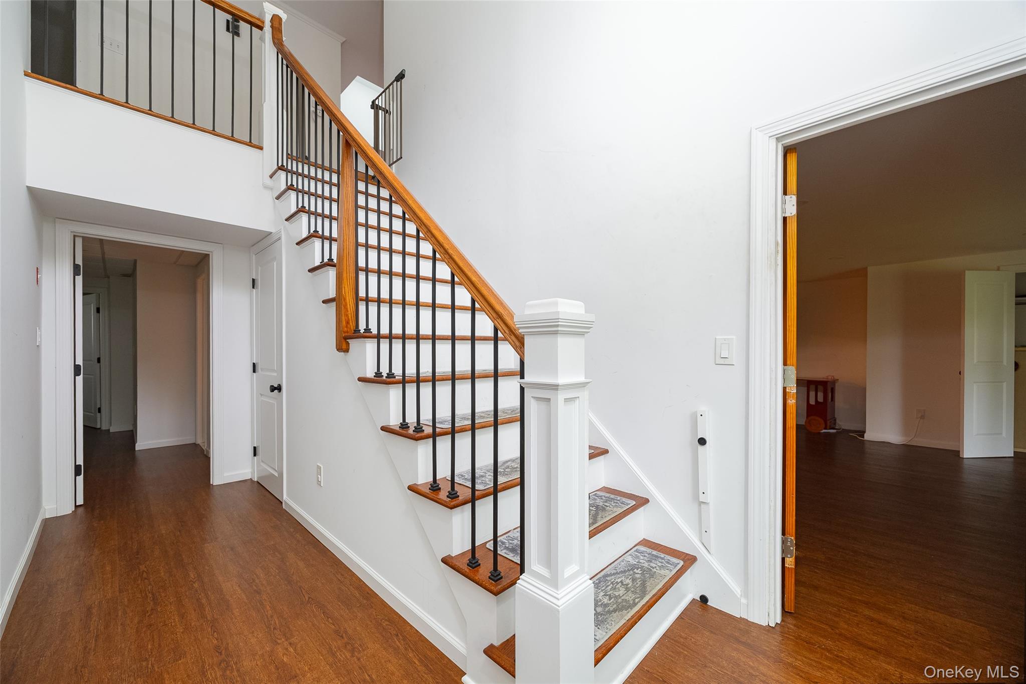 921 West Dover Road Pawling, NY 12564 - Photo 21 of 36 Lower level entryway featuring wood-finish flooring, a staircase with wood treads and a wrought iron baluster system, and white trim