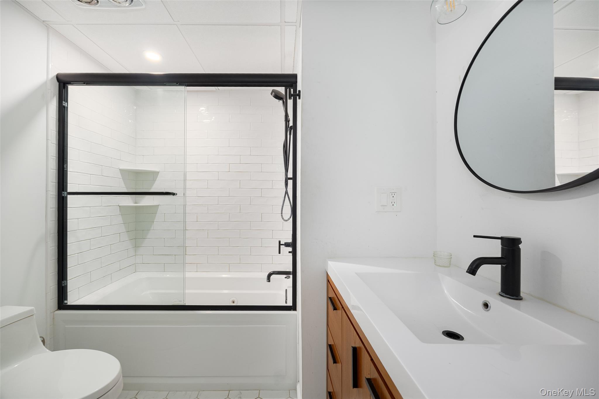 921 West Dover Road Pawling, NY 12564 - Photo 22 of 36 Bathroom featuring a white subway tile shower surround with black-framed glass sliding doors, a matching black shower head, and built-in shelving