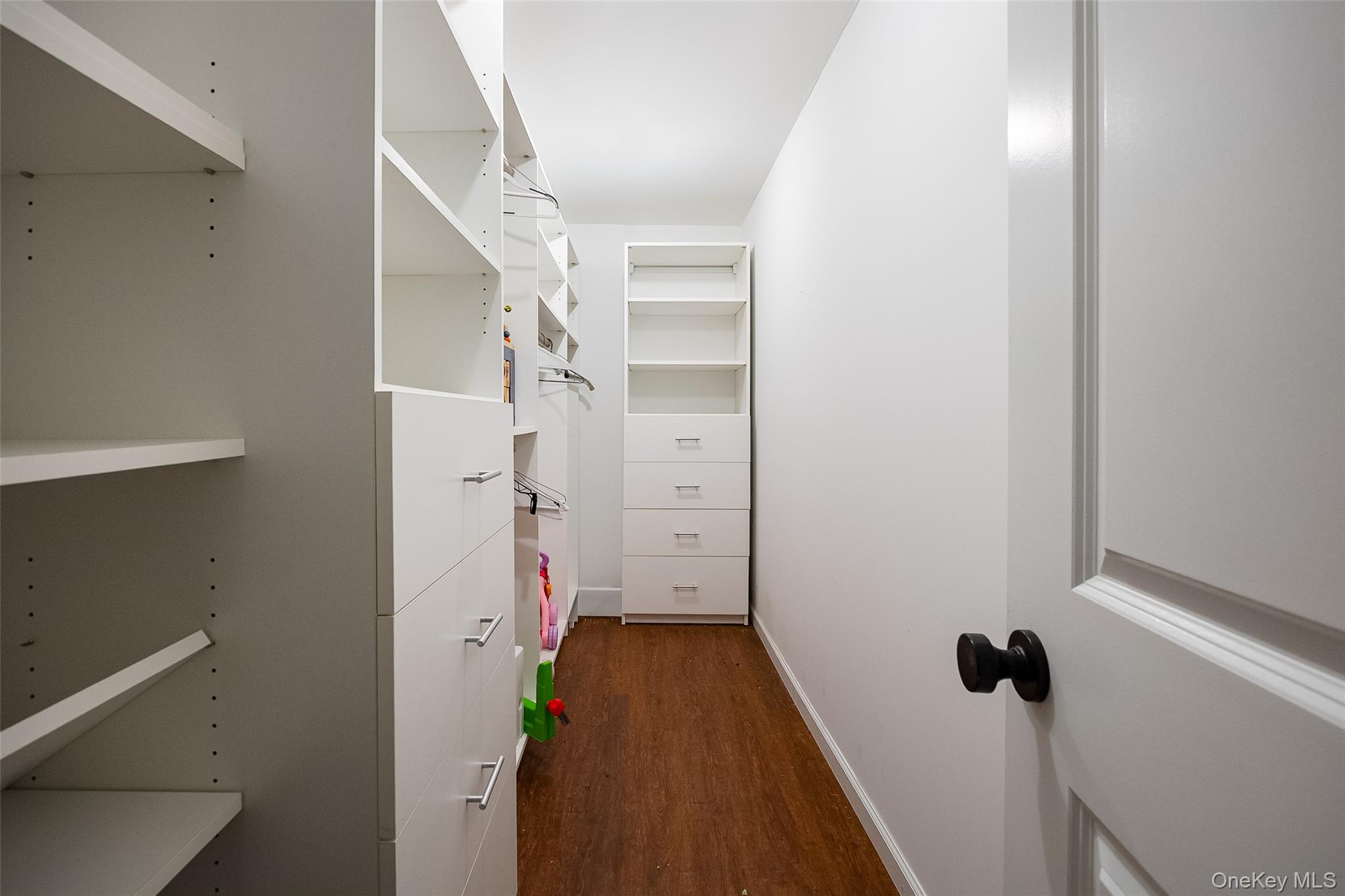 921 West Dover Road Pawling, NY 12564 - Photo 30 of 36 Walk-in closet featuring built-in white shelving, integrated drawers with metal pulls, ample hanging space, and wood-finish flooring