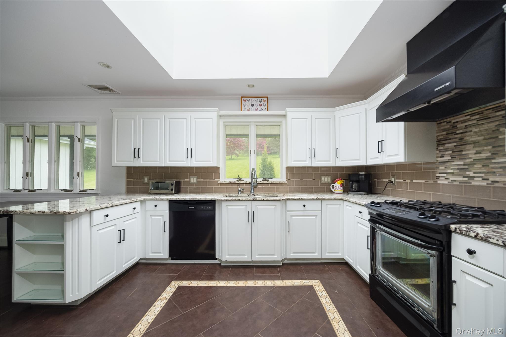 921 West Dover Road Pawling, NY 12564 - Photo 5 of 36 Bright kitchen featuring white cabinetry, stone countertops, a subway tile backsplash, a black gas range with coordinating hood, and a skylight