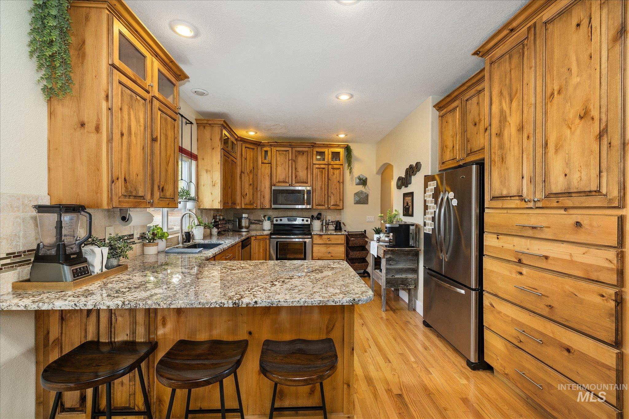 1140 Edgemont Road Emmett, ID 83617 - Photo 4 of 50 Kitchen featuring light wood cabinetry, stone countertops, stainless steel appliances, wood-finish flooring, and recessed lighting
