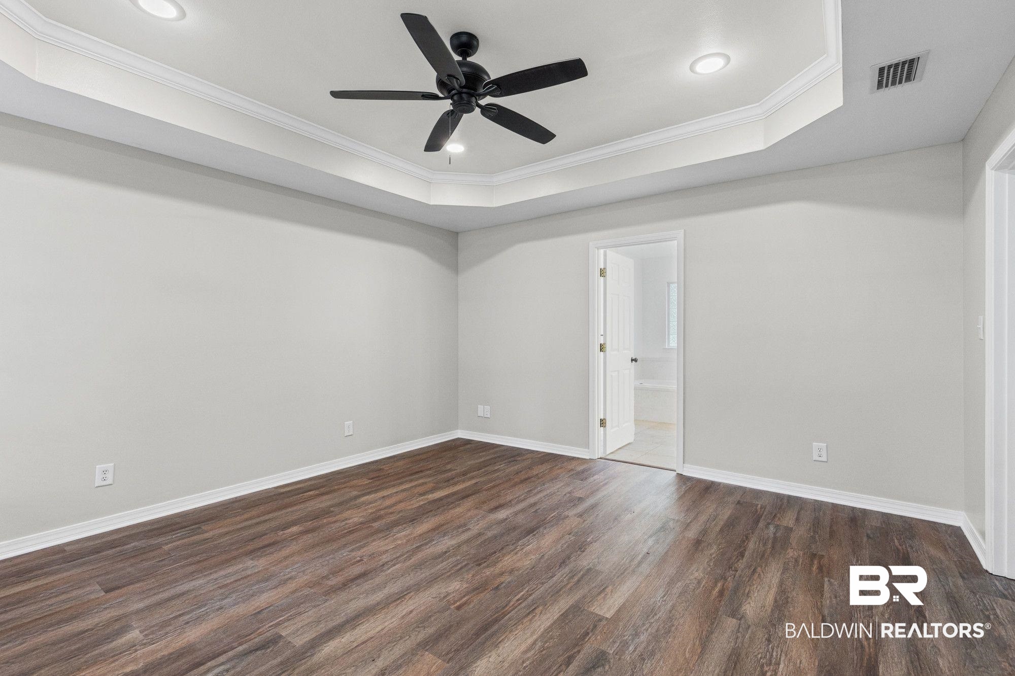 1301 Repoll Road Mobile, AL 36695 - Photo 10 of 21 Spacious room featuring wood-finish flooring and a tray ceiling with a black ceiling fan