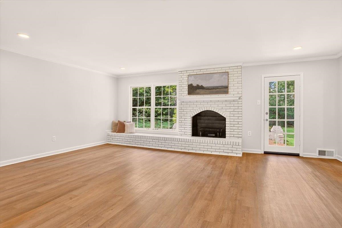 7674 Apple Valley Road Germantown, TN 38138 - Photo 4 of 15 Living space featuring a whitewashed brick fireplace with an arched firebox, wood-finish flooring, and crown molding