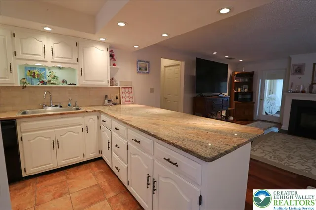 a kitchen with granite countertop white cabinets and refrigerator