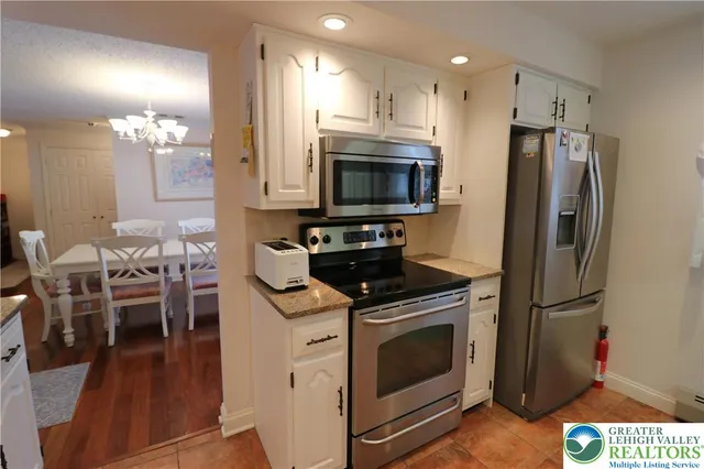 a kitchen with stainless steel appliances a stove a refrigerator a sink a dining table and chairs