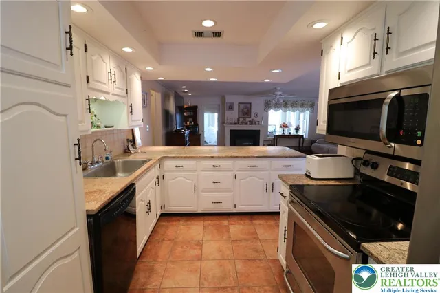 a large kitchen with stainless steel appliances kitchen island granite countertop a sink and cabinets