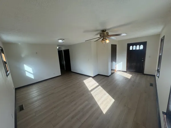an empty room with wooden floor and windows