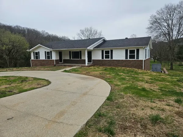 a view of a yard in front of a brick house with large windows