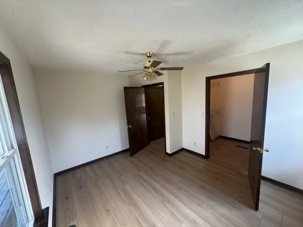 an empty room with wooden floor and a ceiling fan