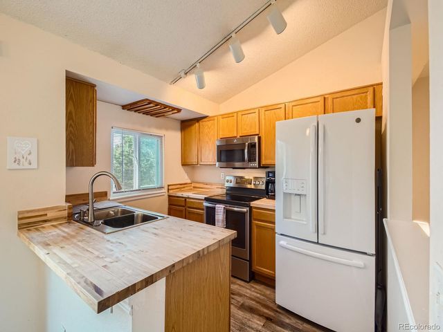 a kitchen with a refrigerator a stove a sink dishwasher and a stove with wooden floor