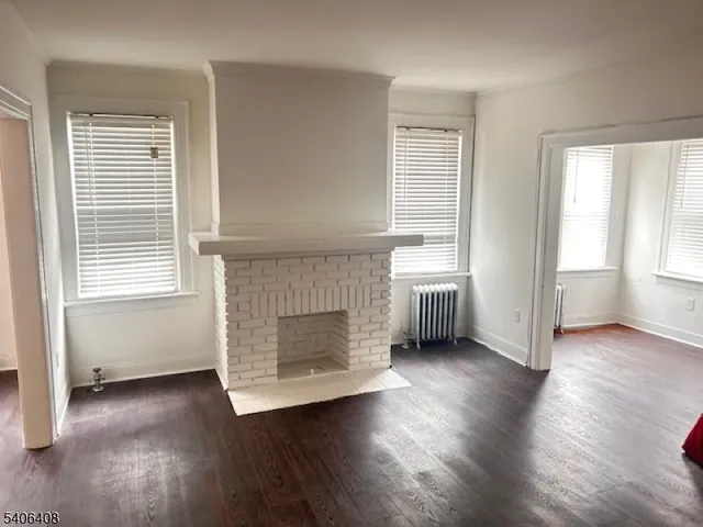 an empty room with wooden floor fireplace and windows