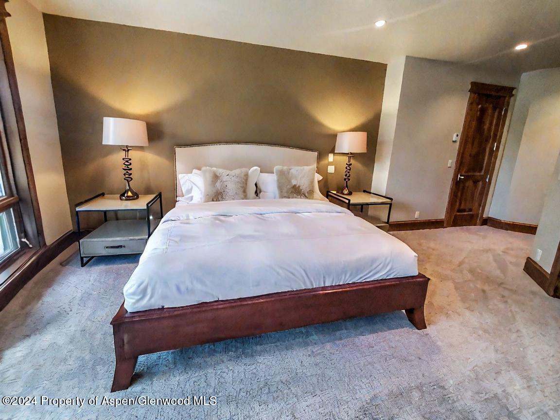 1457 Wood Road Snowmass Village, CO 81615 - Photo 33 of 70 a bedroom with a bed and a lamp with wooden floor