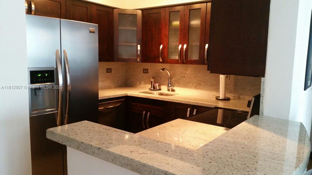 1500 Bay Road, Unit 644S Miami Beach, FL 33139 - Photo 8 of 24 a kitchen with a refrigerator sink and wooden cabinets