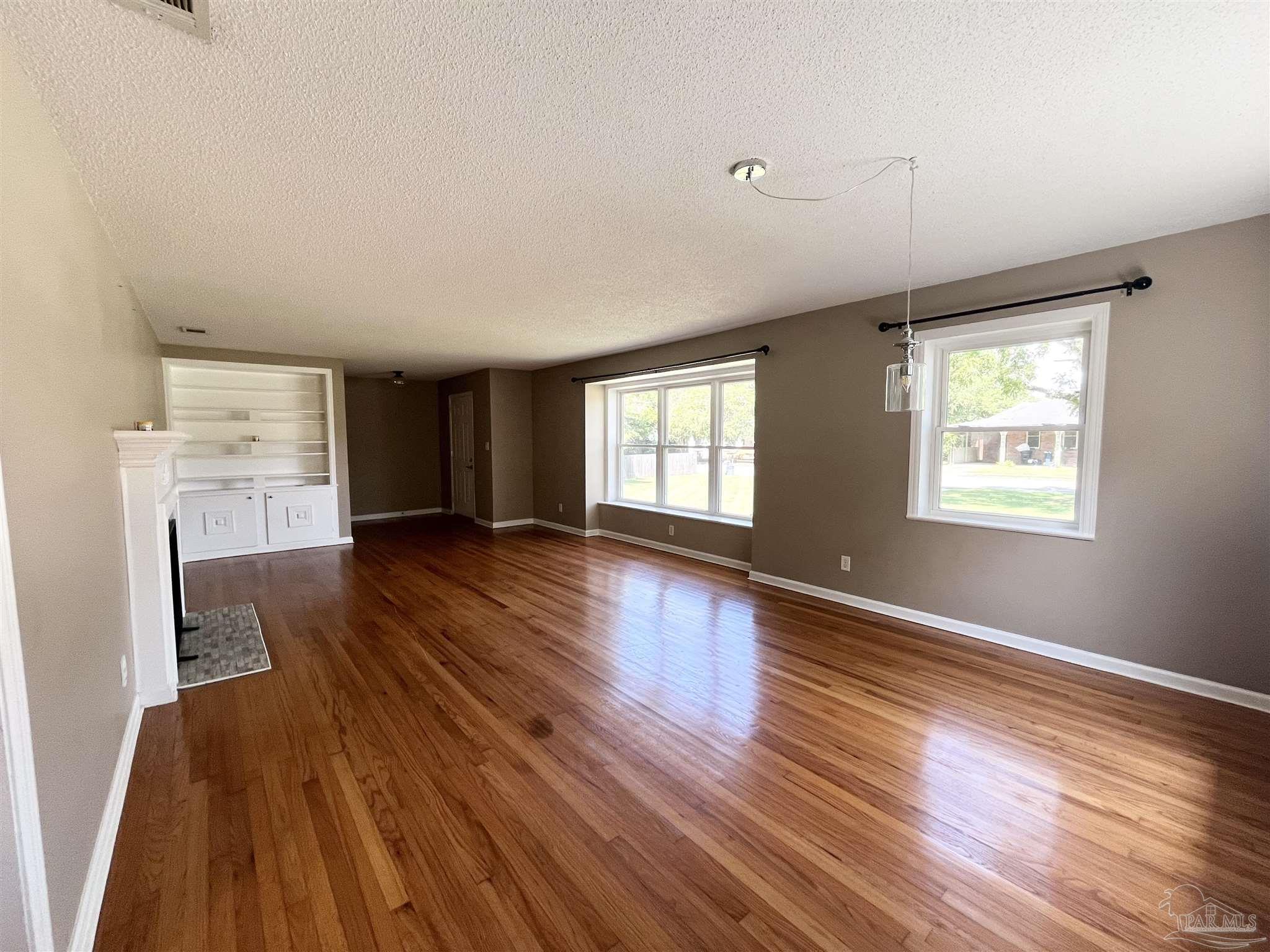 326 East Horner Street Atmore, AL 36502 - Photo 4 of 26 an empty room with wooden floor and windows