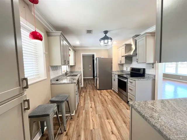 a kitchen with granite countertop kitchen island stainless steel appliances a refrigerator sink stove microwave and cabinets