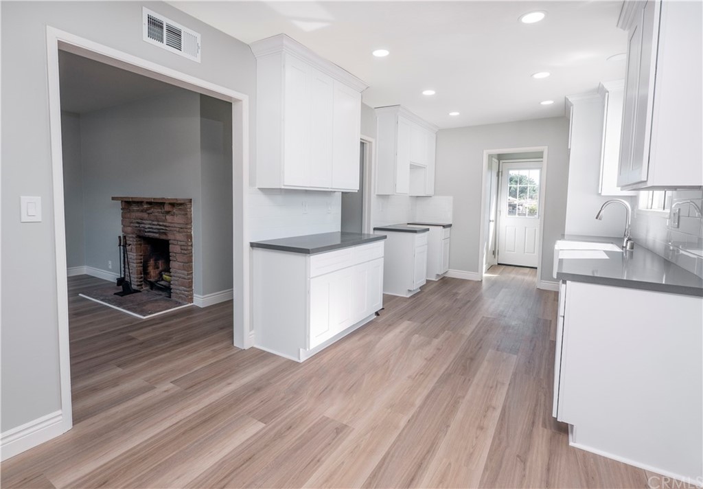 150 East Gladstone Street San Dimas, CA 91773 - Photo 13 of 37 a kitchen with a sink a stove cabinets and wooden floor