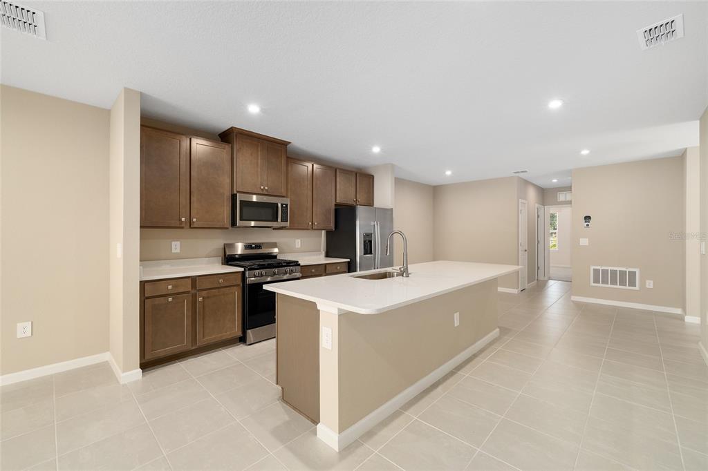 1183 Turtle Is Road Lady Lake, FL 32159 - Photo 15 of 39 a kitchen with stainless steel appliances granite countertop a sink a stove top oven a refrigerator with grey cabinets