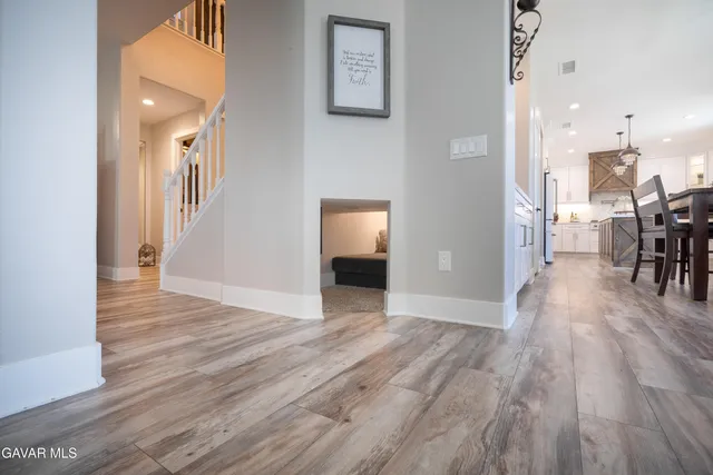 a view of a hallway with wooden floor windows and a kitchen view