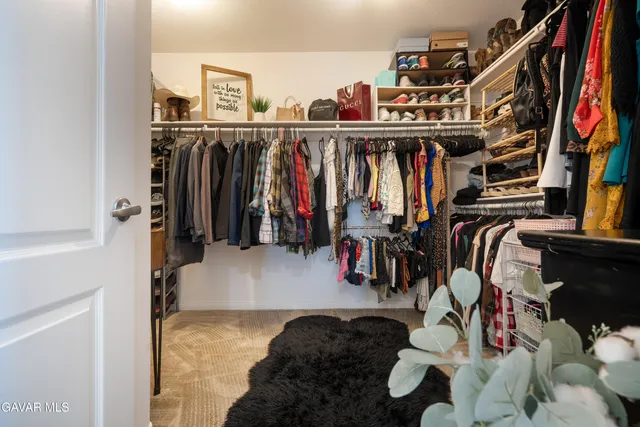 a view of walk in closet with clothes and shoes