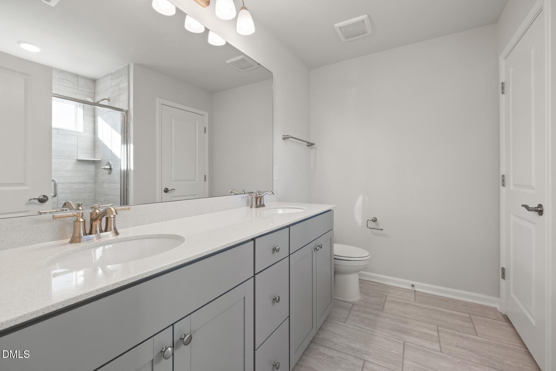 204 Armorial Court Willow Spring, NC 27592 - Photo 14 of 26 a bathroom with a double vanity sink and a toilet