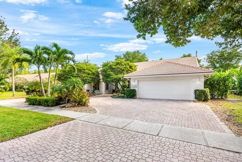 a white house with a yard plants and palm trees