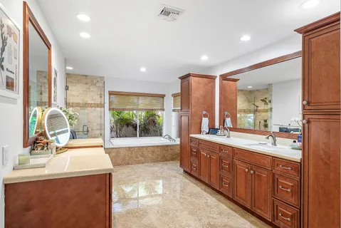a large bathroom with a double vanity sink a large mirror and a bathtub