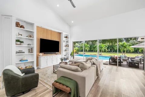 a living room with furniture a flat screen tv and a floor to ceiling window