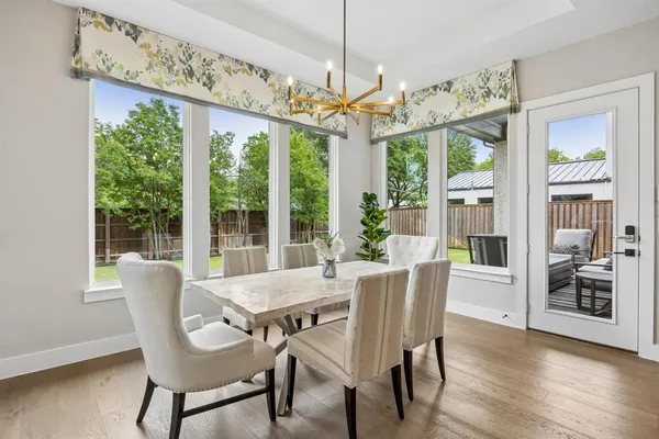 a dining room with wooden floor a chandelier a wooden table and chairs