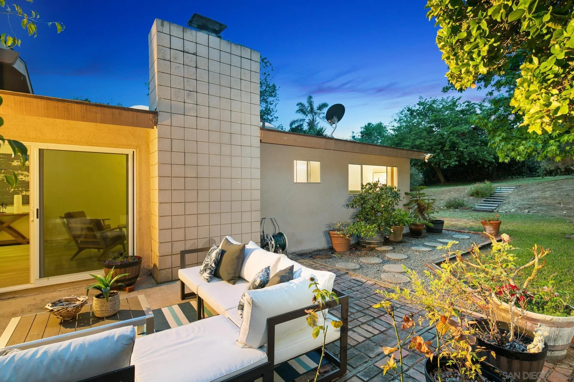 916 Crest Drive Encinitas, CA 92024 - Photo 4 of 47 a view of a patio with couches table and chairs under an umbrella with potted plants