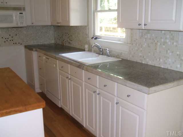 4217 Pope Road Durham, NC 27707 - Photo 5 of 10 a kitchen with granite countertop a sink a stove and dishwasher with wooden floor