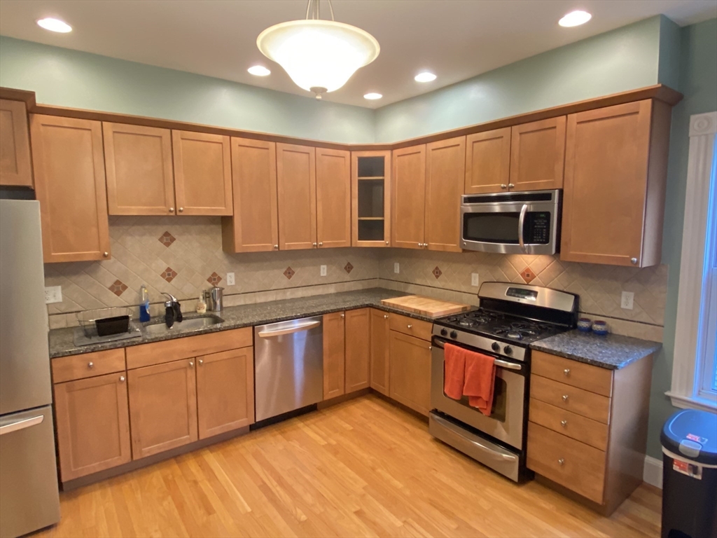 a kitchen with stainless steel appliances granite countertop a stove a sink and a microwave
