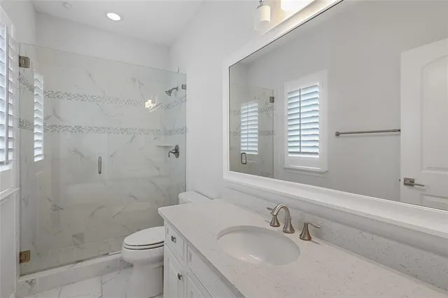 a bathroom with a granite countertop sink a toilet and shower
