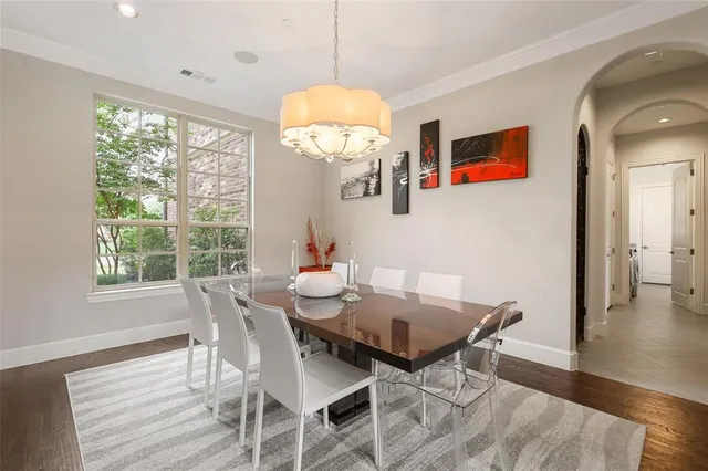 a dining room with wooden floor a chandelier a wooden table and chairs