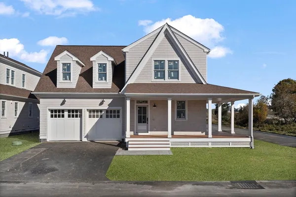 a view of a white house with a large windows and a yard with plants and large tree