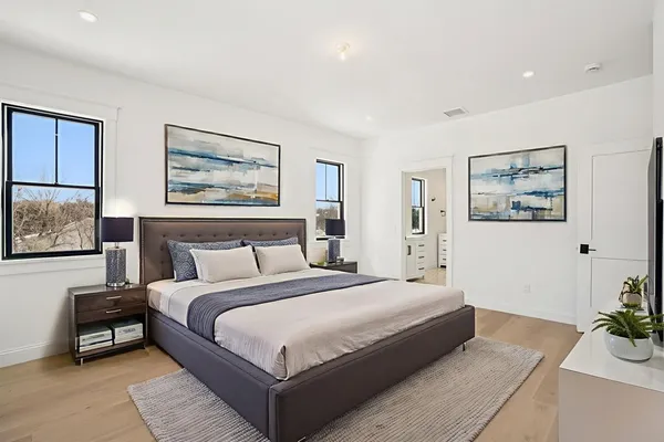 a spacious bedroom with a bed a couch and paintings on the wall